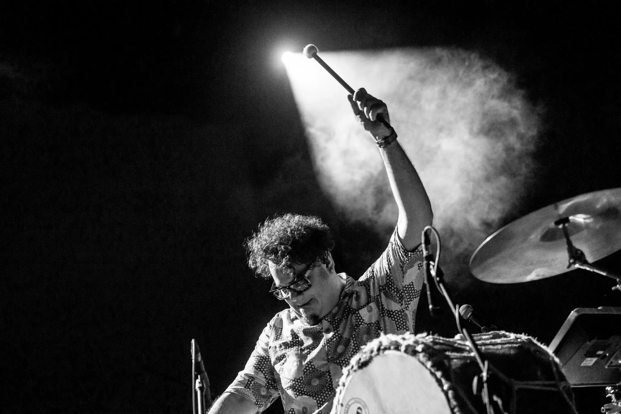 Mr. Pauer performing live percussion onstage, raising a drum mallet